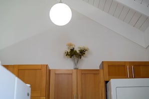 A kitchen with wooden cabinets, a white refrigerator, and a vase with flowers on the wall. - Richmond Retreat Pool Gym Gated Beach Access (St. Ann's Bay)