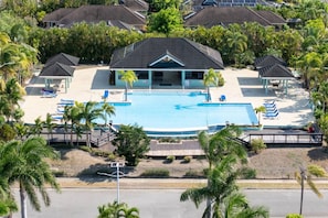 Un resort con una amplia piscina, varias zonas de descanso y un pabellón cubierto.