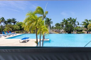 Una piscina con sillones de descanso y palmeras.