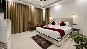 Habitación de hotel con una cama grande, ventilador de techo, televisor y minibar.