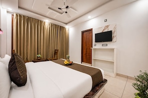 A hotel room with a bed, a TV, a wooden door, and a plant. - Chaitanya Homes Kasauli (Kasauli)
