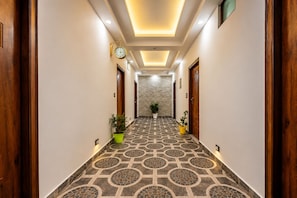 A hallway with patterned flooring, wooden doors, a clock, and potted plants. - Chaitanya Homes Kasauli (Kasauli)