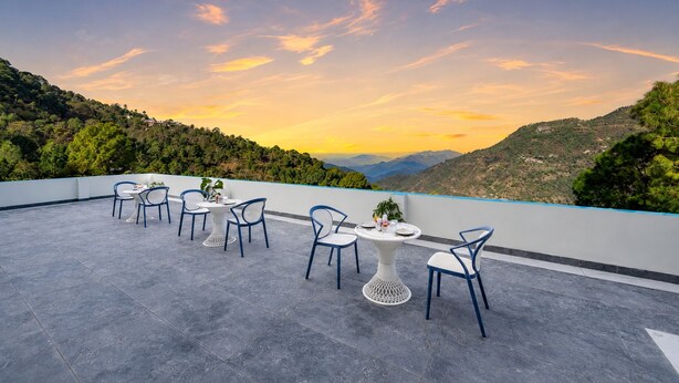 Una terraza con mesas y sillas, con vistas a un paisaje montañoso.