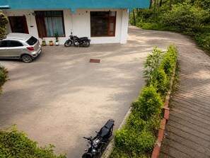 A residential area with a paved driveway, a parked car, and a motorcycle. - Chaitanya Homes Kasauli (Kasauli)