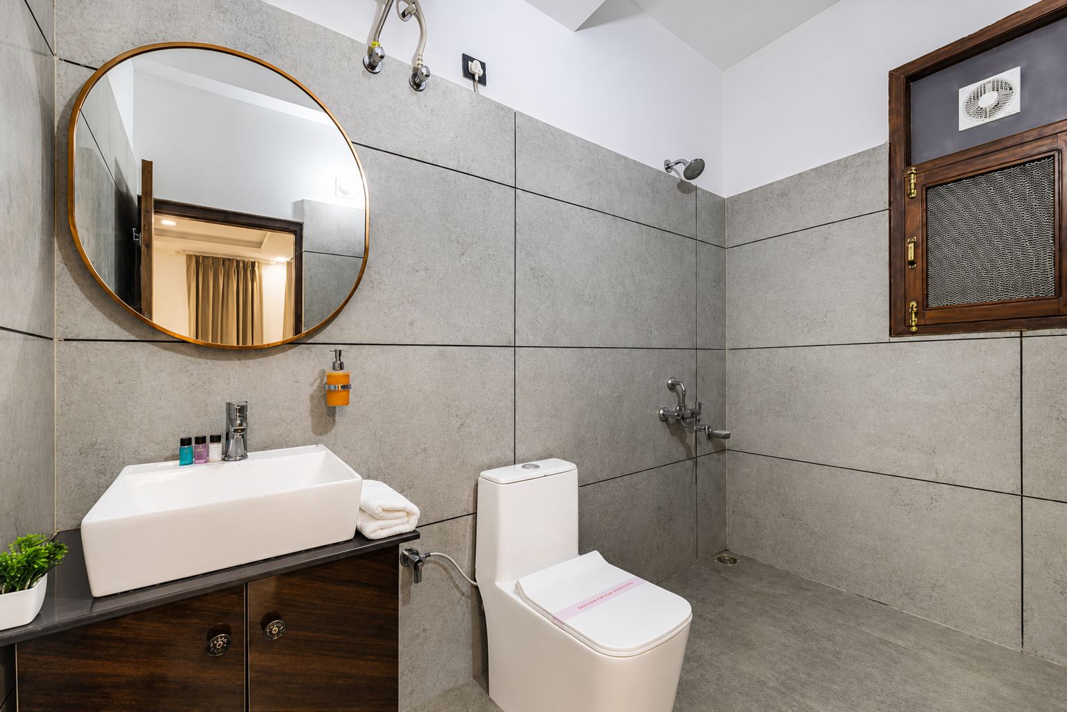 Een moderne badkamer met een grote spiegel, een wastafel, toilet en douche.