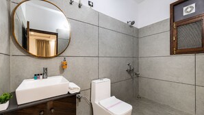 Un baño moderno con un espejo grande, un lavamanos, un inodoro y una ducha.