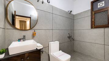 Een moderne badkamer met een grote spiegel, een wastafel, toilet en douche.