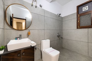 Un baño moderno con un espejo grande, un lavamanos, un inodoro y una ducha.