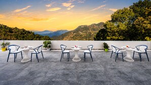 Una terraza con mobiliario exterior y una vista panorámica a las montañas.