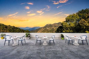 Una terraza con mobiliario exterior y una vista panorámica a las montañas.