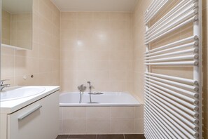 Ein Badezimmer mit einer Badewanne, einem Waschbecken und einem Handtuchhalter.