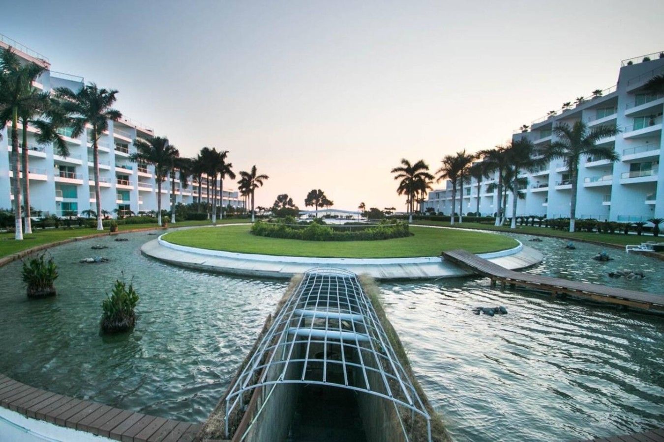 A hotel with a central water feature, palm trees, and a modern building facade.