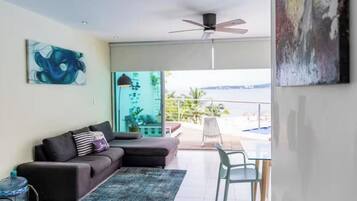 Un salon moderne avec un canapé, une table en verre et une vue sur la mer.