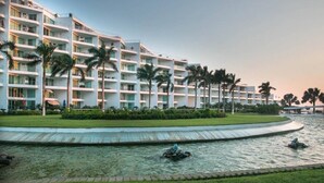 Un hotel con diversi piani, una piscina e palme.