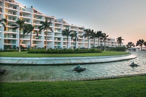 Um hotel com vários andares, piscina e palmeiras.
