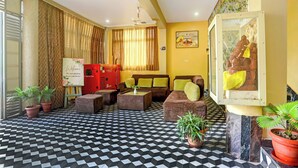 A hotel lobby with a checkered floor, sofas, a red cabinet, and a wall-mounted picture. - Super Hotel O New Marine Drive Puri (Puri)