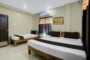 Una habitación de hotel con dos camas individuales, un cabecero de madera, un aire acondicionado de pared y un cuadro decorativo.