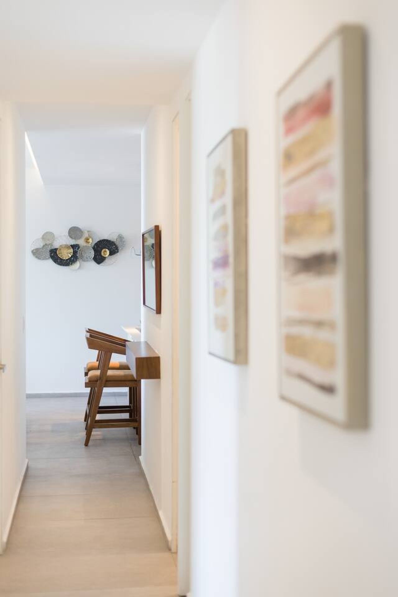 A hallway with a dining area, featuring a wooden chair and a table.