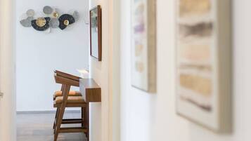 A hallway with a dining area, featuring a wooden chair and a table.