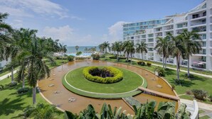 A resort with a circular water feature, palm trees, and a beach view. - 406 Increible depa con jacuzzi priv y vista al mar (Nuevo Vallarta)