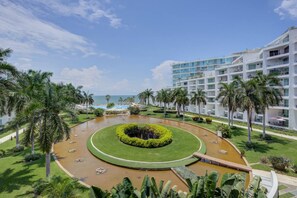 Ein Resort mit einem kreisförmigen Wasserspiel, Palmen und Blick auf den Strand.
