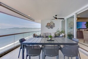 A balcony with a dining table, chairs, and a sofa. There is a view of the sea and a ceiling fan. - Depto. Playa Vista Mar Villa Magna Nuevo Vallarta (Nuevo Nayarit)