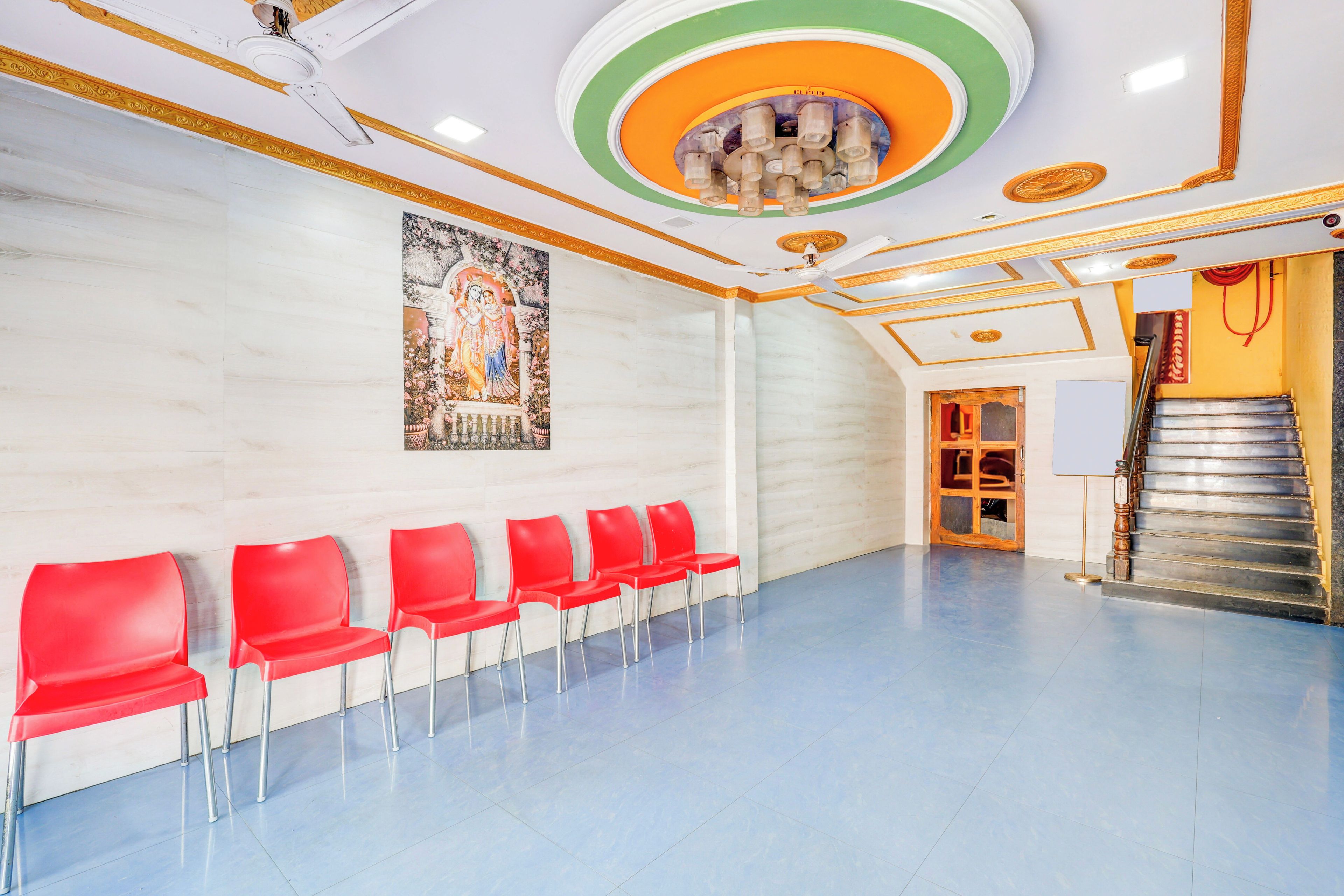 A waiting area with red chairs, a staircase, and a mural on the wall.