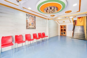 A waiting area with red chairs, a staircase, and a mural on the wall.