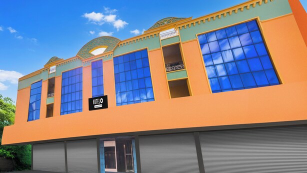 A building with large windows, a sign reading 'HOTEL', and a garage door. - Hotel O Rayagada Downtown (Rayagada)