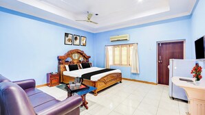 A hotel room with a bed, a sofa, a desk with a vase of flowers, a ceiling fan, and a window with curtains. - Hotel O Rayagada Downtown (Rayagada)