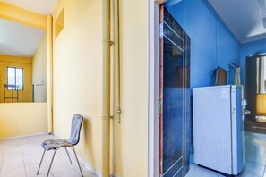 A room with a chair, a refrigerator, and a door leading to another room.