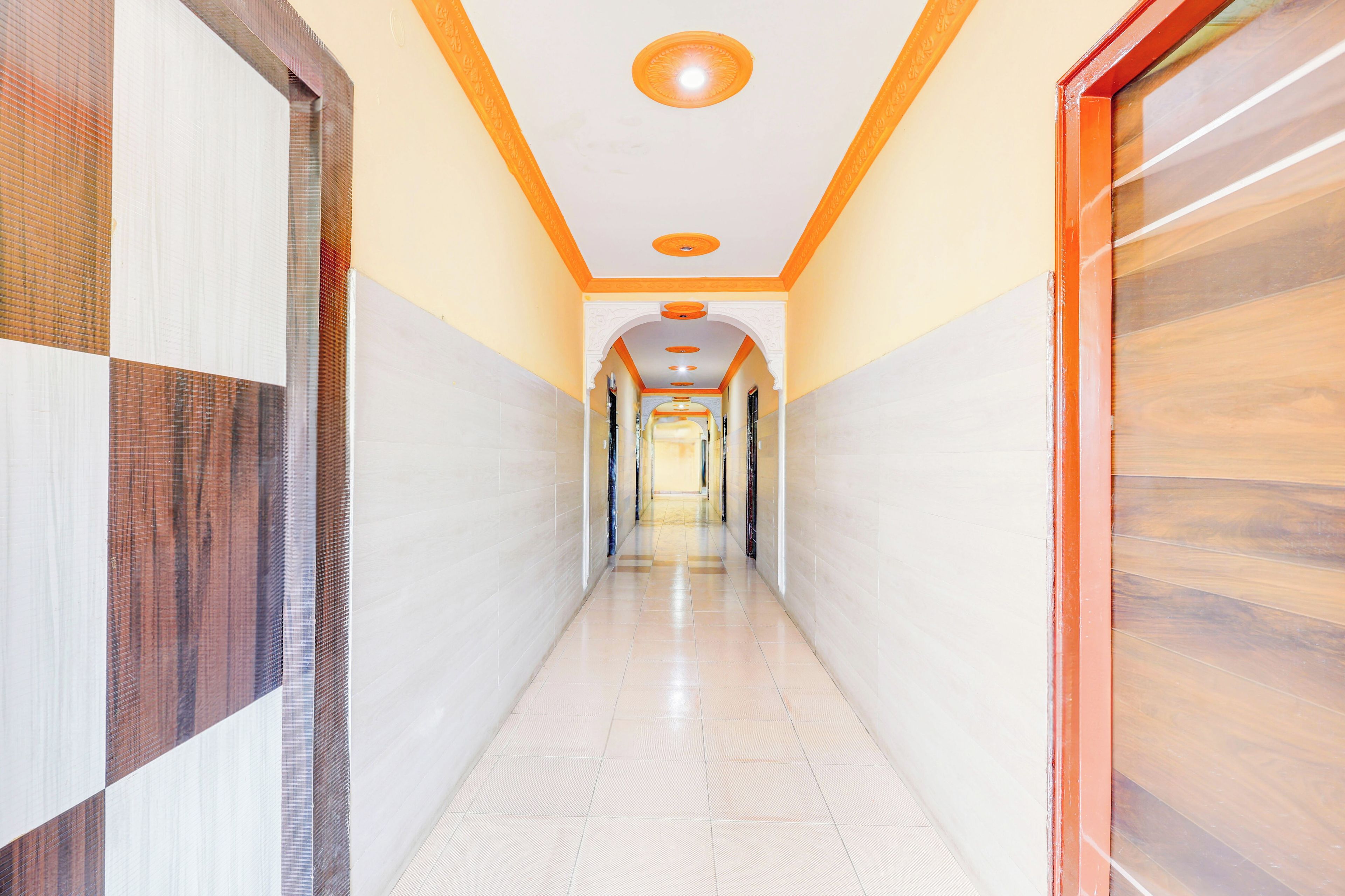 A corridor with tiled walls and a tiled floor, leading to a door with a glass panel.