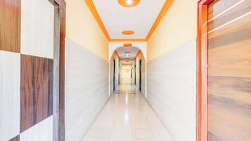A corridor with tiled walls and a tiled floor, leading to a door with a glass panel.