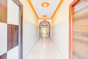 A corridor with tiled walls and a tiled floor, leading to a door with a glass panel.
