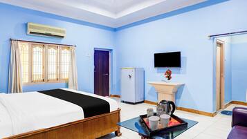 A hotel room with a bed, a small table with a tray, a sink, a television, and a door.