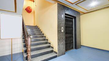 A staircase with a handrail, a door with a metal gate, and a whiteboard on the wall.
