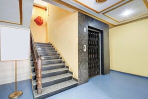 A staircase with a handrail, a door with a metal gate, and a whiteboard on the wall. - Hotel O Rayagada Downtown (Rayagarha)