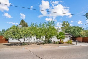 A residential area with a white building, a street, and a clear sky. - Prana Hacienda Near U of A Fire Pit Garden (Tucson)