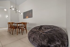 Ein Essbereich mit Tisch und Stühlen, einem großen Sitzsack und einer wandmontierten Leuchte.