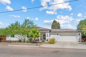 A single-story house with a garage, surrounded by various plants and trees. - Prana Hacienda Near U of A Fire Pit Garden (Tucson)