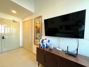 A hotel room with a flat-screen TV mounted on the wall, a wooden dresser, and a door leading to another room. - Departamento/Estudio en Playa Royale, Nuevo Vta. (Nuevo Vallarta)