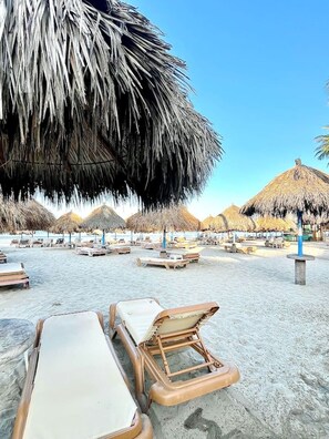 A beach with thatched umbrellas and lounge chairs. - Departamento/Estudio en Playa Royale, Nuevo Vta. (Nuevo Vallarta)