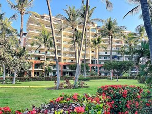 A multi-story hotel with balconies, surrounded by palm trees and well-maintained lawns. - Departamento/Estudio en Playa Royale, Nuevo Vta. (Nuevo Vallarta)