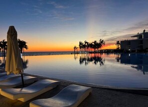 Una piscina infinita con vistas a la puesta de sol y palmeras.
