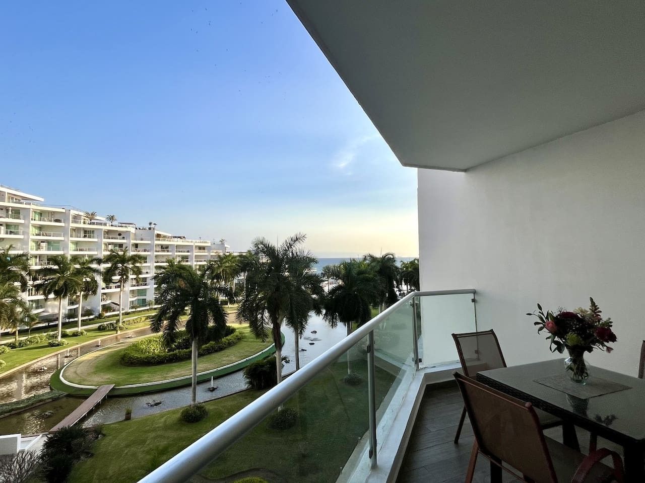 A balcony with a view of a waterway, palm trees, and a building complex.