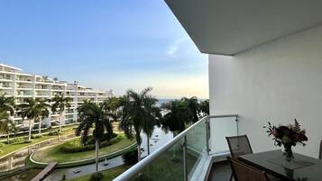 A balcony with a view of a waterway, palm trees, and a building complex.