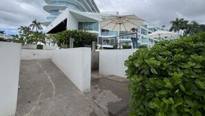 Un hotel moderno con facciata curva, area salotto esterna e verdeggiante vegetazione.
