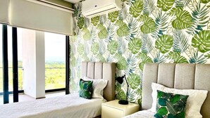 Una camera d'albergo con due letti, una finestra vista e una parete decorata con un motivo a foglia.