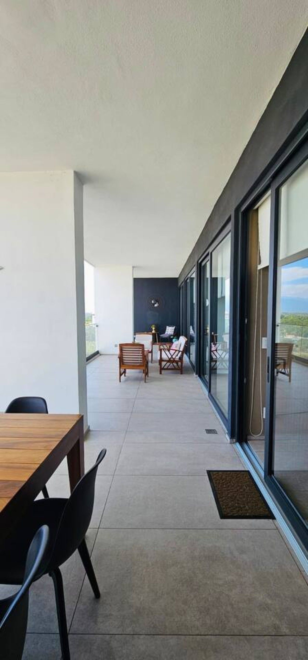 Un balcon extérieur moderne doté d’un espace repas, de sièges et offrant une vue sur le paysage.