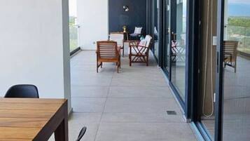 Un balcon extérieur moderne doté d’un espace repas, de sièges et offrant une vue sur le paysage.